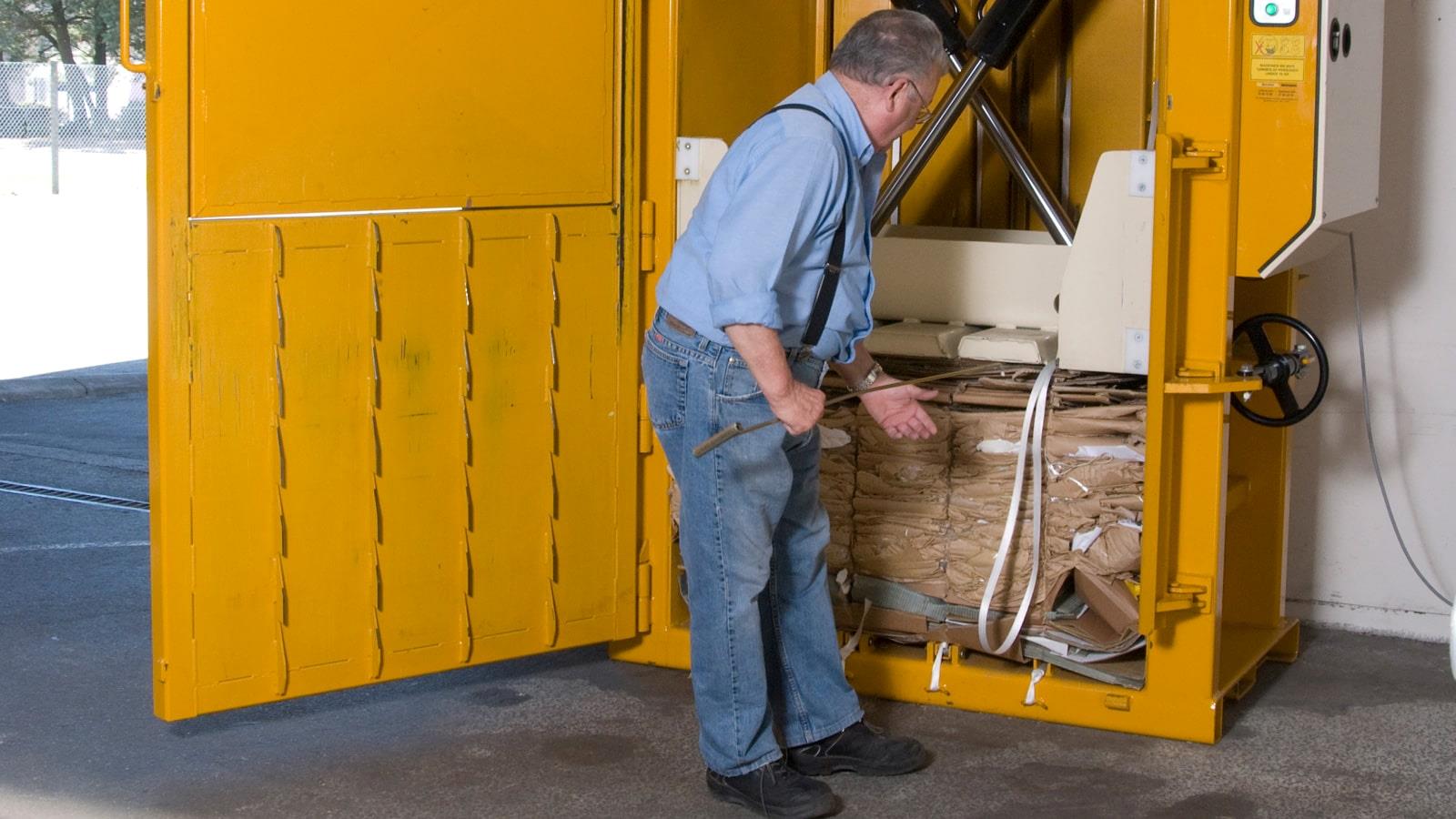 Employee at RewAir throws cardboard waste into a Bramidan baler