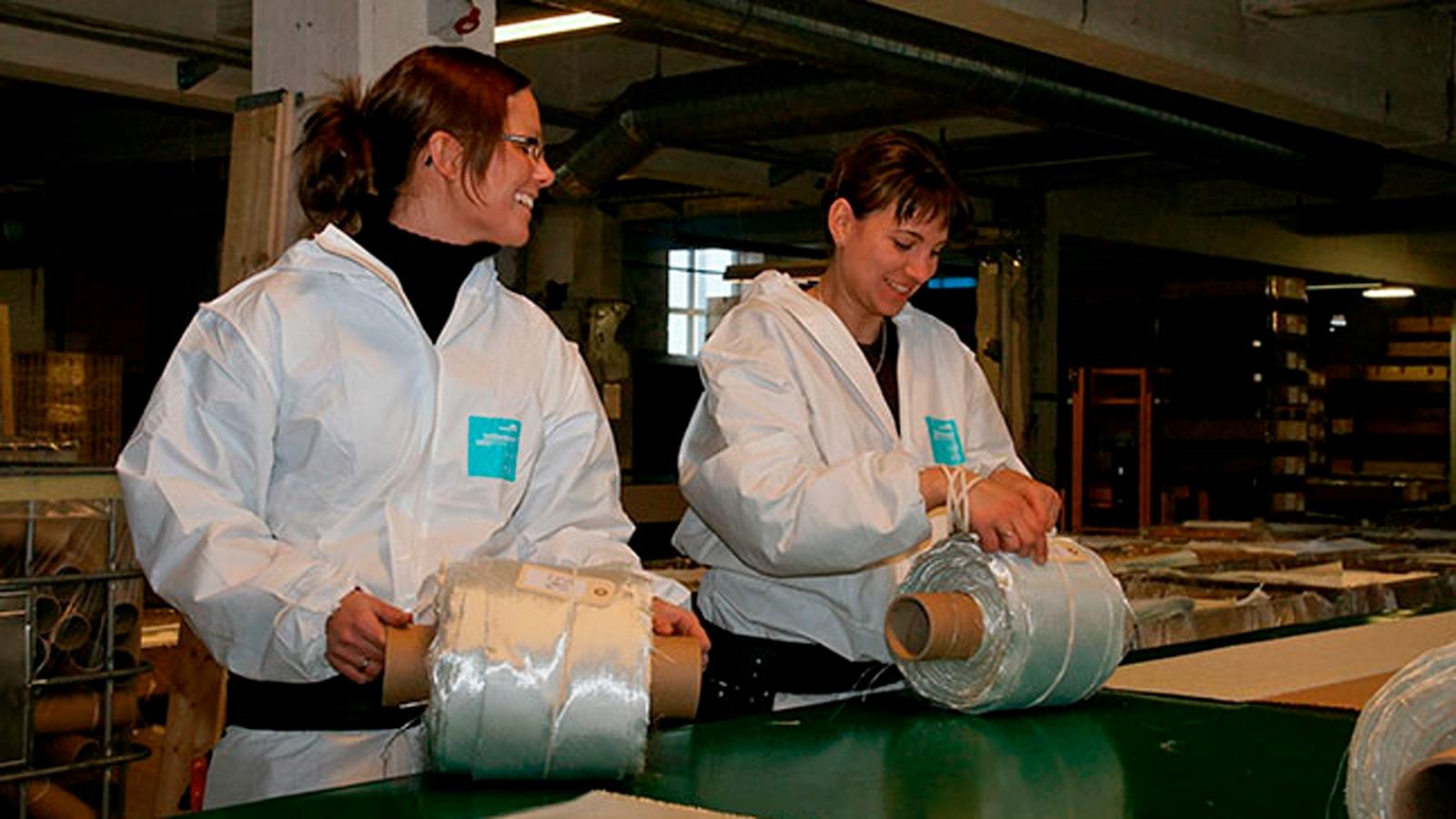 Two female employees at RewAir put labels on glass fibre rolls