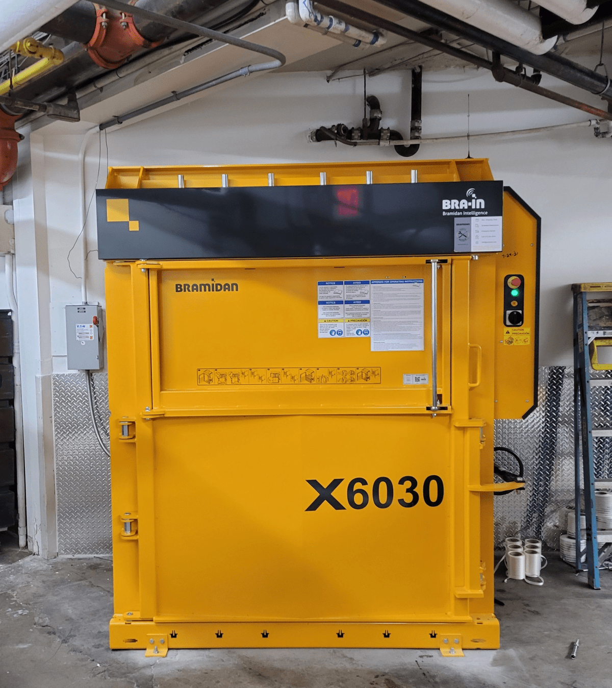 Yellow Bramidan baler sits in front of concrete wall