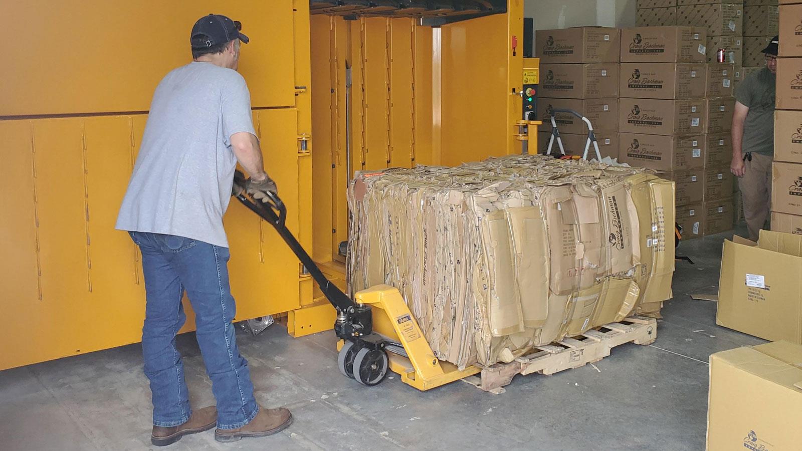 Man removing finished cardboard bale with a palletjack